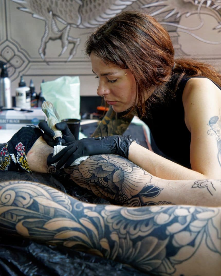 A tattoo artist at work on a client's arm
